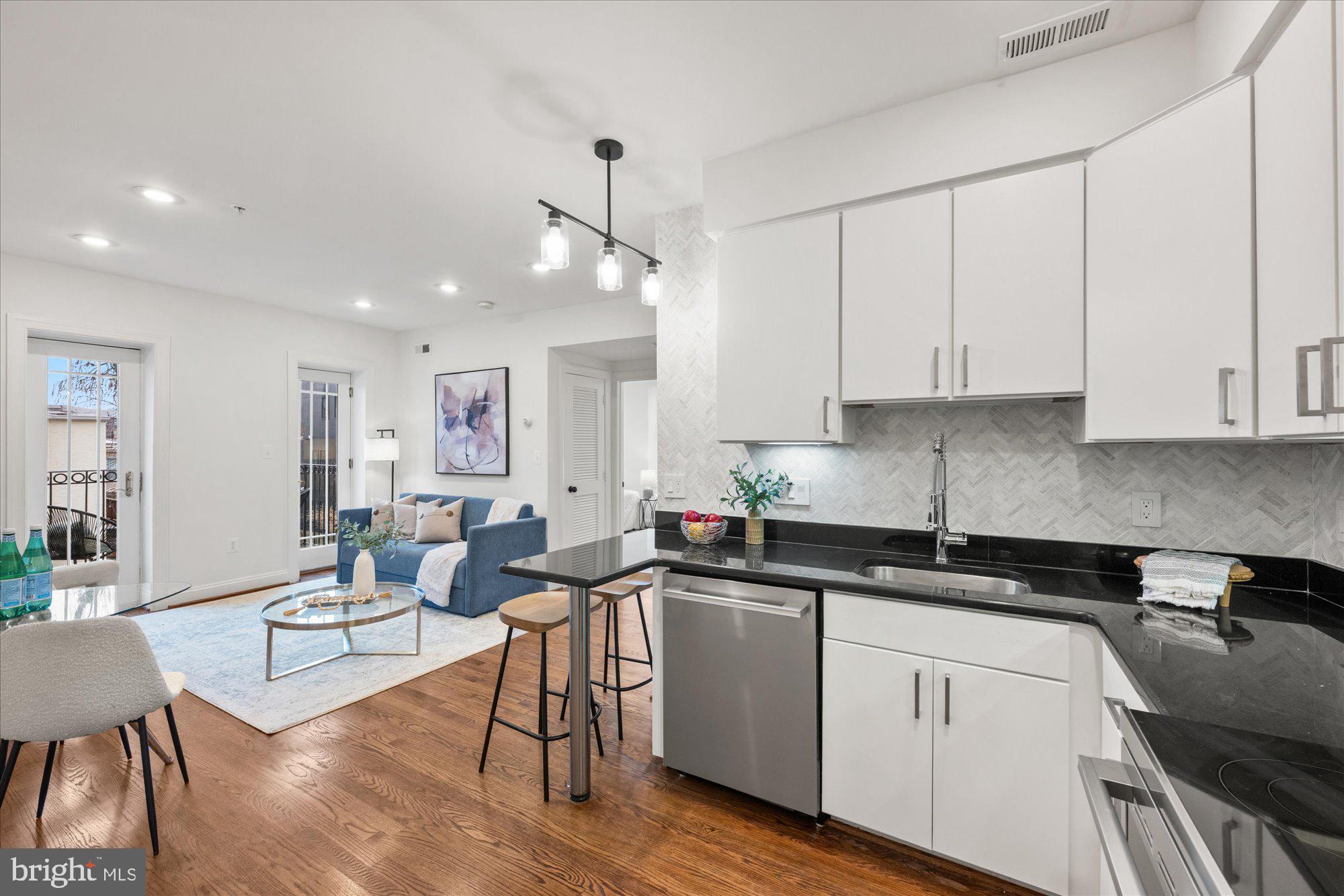 660 Morton Place Northeast, Unit 5 Washington, DC 20002 - Photo 11 of 21 a kitchen with stainless steel appliances granite countertop a sink a stove a dining table and chairs with wooden floor