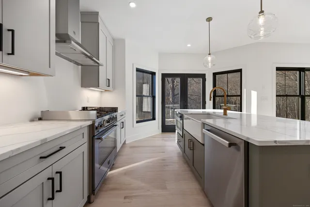 a kitchen with stainless steel appliances granite countertop a sink a stove and a wooden floors