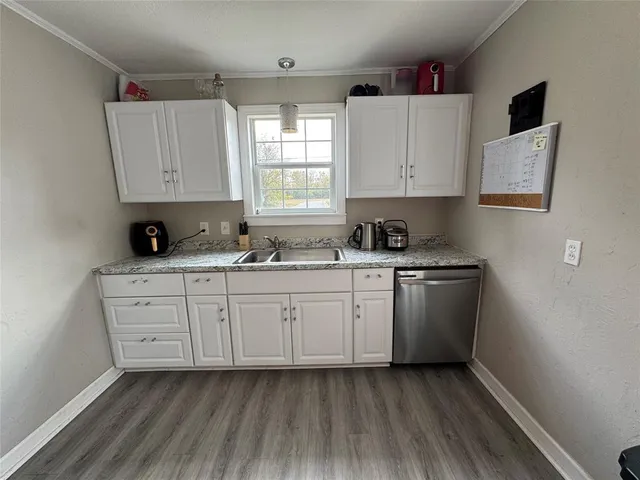 a kitchen with granite countertop white cabinets sink and window