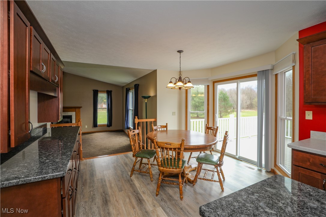 12565 Alpha Road Hiram, OH 44234 - Photo 7 of 50 Dining room featuring an inviting chandelier, wood finished floors, a tiled fireplace, and vaulted ceiling