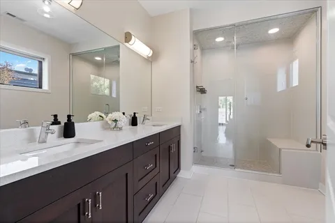 a spacious bathroom with a double vanity sink a large mirror and shower