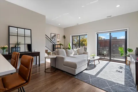 a living room with furniture large windows and wooden floor