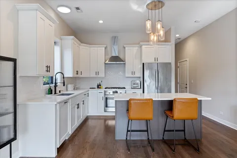 a kitchen with stainless steel appliances a dining table chairs sink and cabinets