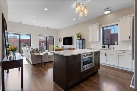 a kitchen with stainless steel appliances granite countertop a stove top oven a sink dishwasher a dining table and chairs with wooden floor