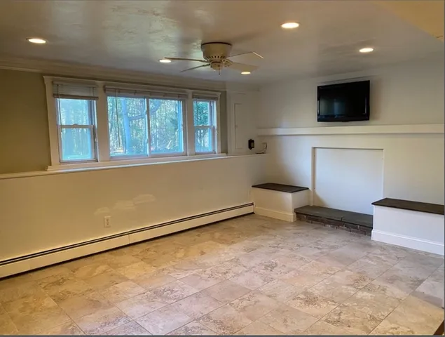 a view of an empty room with a window and a kitchen