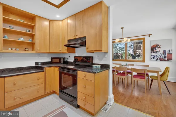a kitchen with stainless steel appliances granite countertop a stove top oven a sink a dining table and chairs with wooden floor