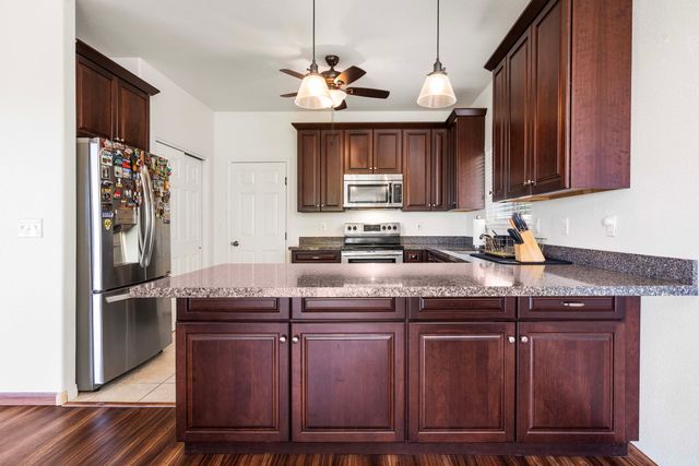 a kitchen with kitchen island granite countertop a sink cabinets and stainless steel appliances
