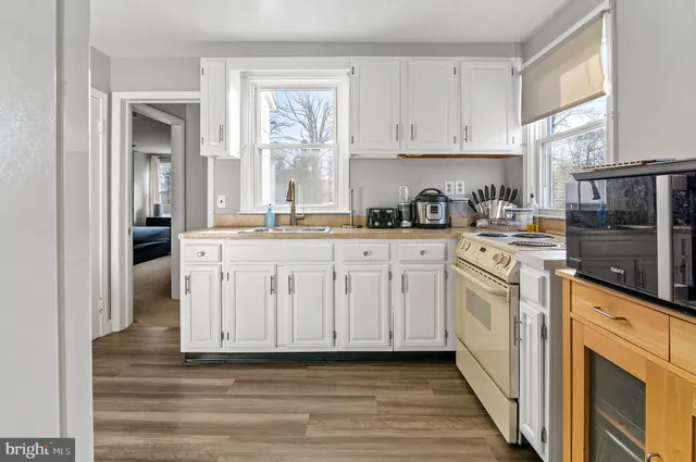 a kitchen with stainless steel appliances granite countertop a sink and cabinets with wooden floor