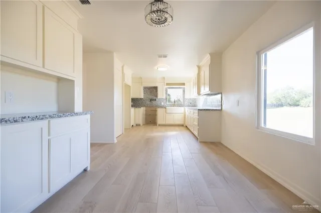 a kitchen with stainless steel appliances granite countertop a stove a sink and white cabinets with wooden floor