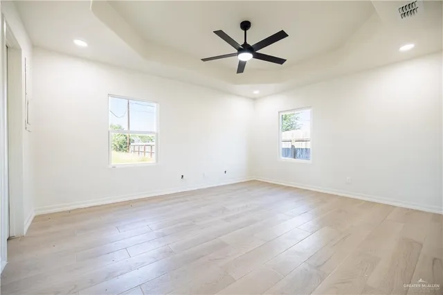 an empty room with wooden floor and windows