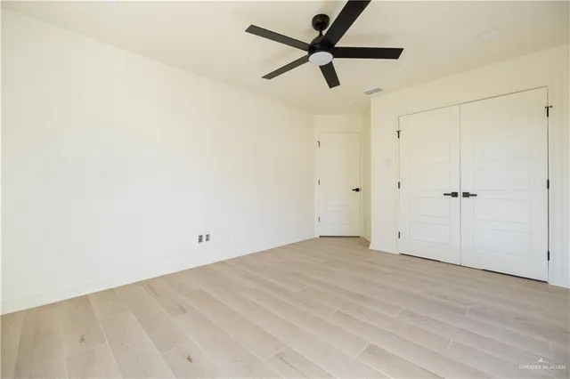 an empty room with a ceiling fan and wooden floor