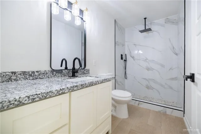 a bathroom with a granite countertop sink a toilet and a mirror