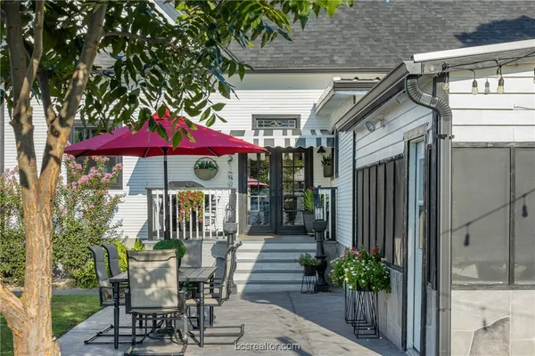 a view of a patio with a table and chairs under an umbrella with a small yard