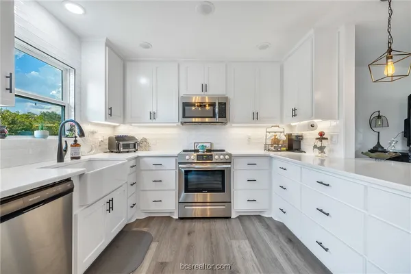 a kitchen with cabinets stainless steel appliances and a window