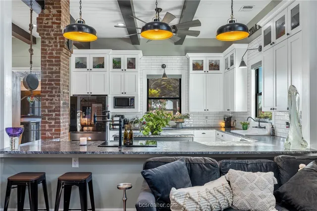 a kitchen with stainless steel appliances a stove a sink and a dining table with chairs