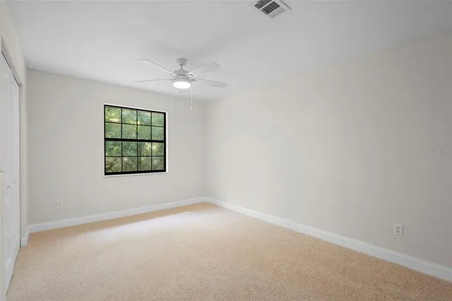 an empty room with windows and fan