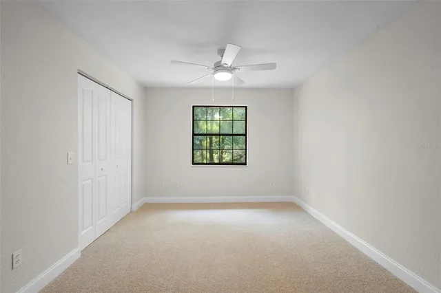 an empty room with windows and ceiling fan