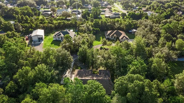 an aerial view of residential house with outdoor space and trees all around
