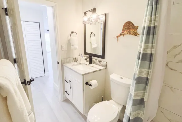 a bathroom with a sink a toilet a mirror and shower