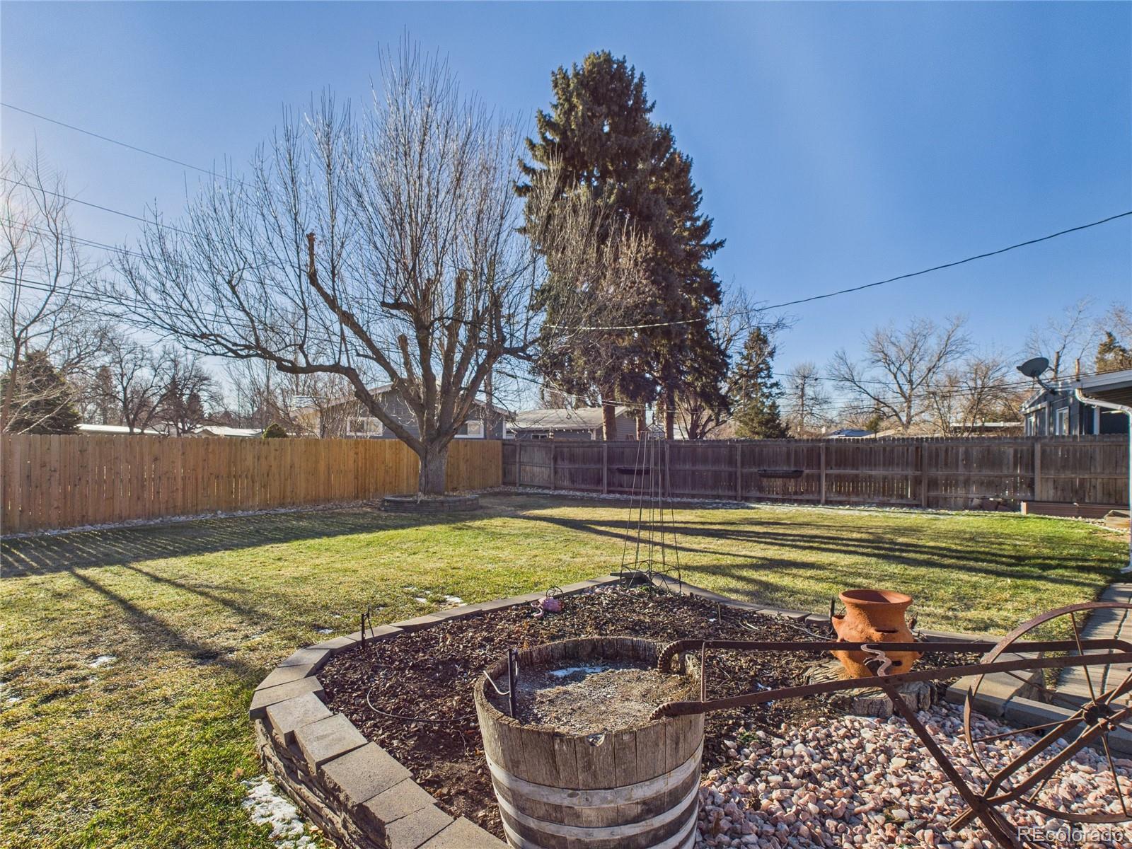 1360 South Ivy Way Denver, CO 80224 - Photo 21 of 23 a view of a backyard with lawn chairs under a large tree