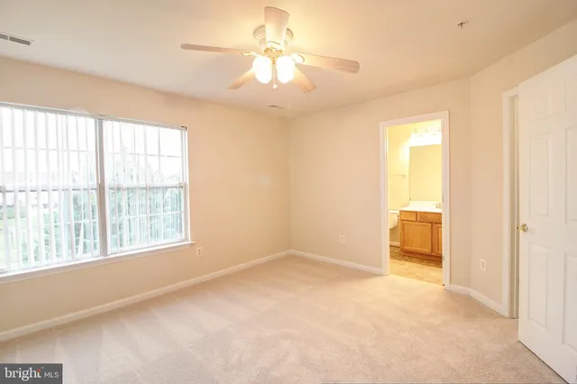 an empty room with a window and a fan