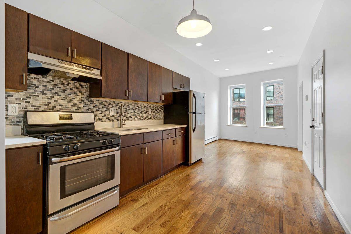 1235 Decatur Street, Unit 3 Brooklyn, NY 11207 - Photo 1 of 1 a kitchen with granite countertop wooden floors and stainless steel appliances