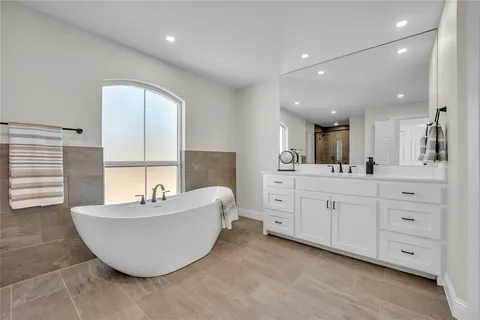 a spacious bathroom with a double vanity sink a mirror and a bathtub