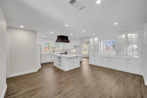 a large white kitchen with kitchen island a sink stainless steel appliances and cabinets