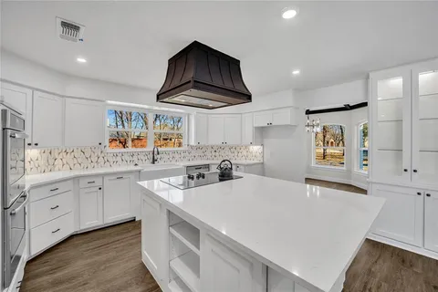 a kitchen with stainless steel appliances a sink a stove a refrigerator and white cabinets