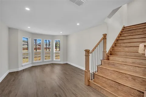 a view of an empty room with wooden floor and stairs