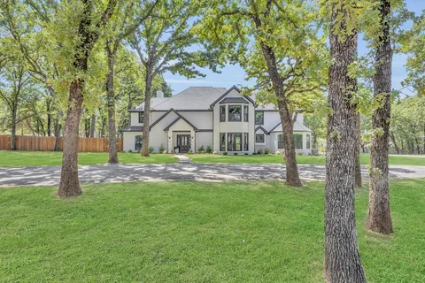a view of house with a big yard and large trees