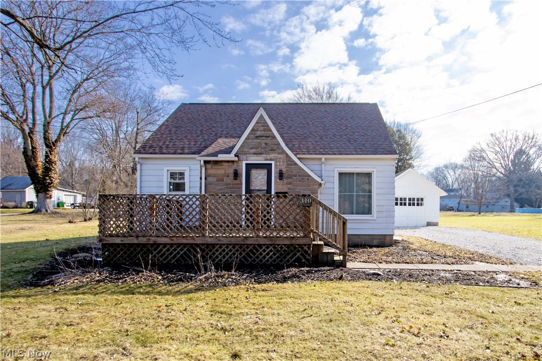 310 North Seneca Street Rittman, OH 44270 - Photo 28 of 28 View of front of house with a front lawn, a shingled roof, a wooden deck, a garage, and an outbuilding