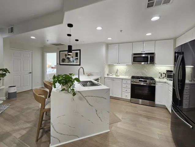 a kitchen with stainless steel appliances kitchen island granite countertop a refrigerator and a stove top oven