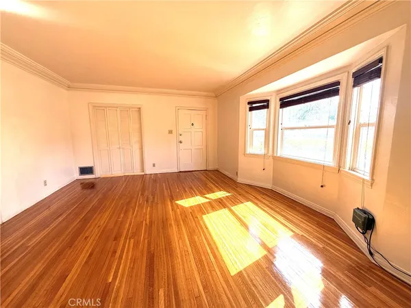 a view of empty room with wooden floor and fan