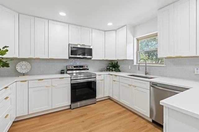 a kitchen with granite countertop a sink cabinets and stainless steel appliances
