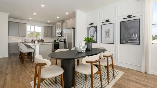 a kitchen with stainless steel appliances kitchen island granite countertop a dining table chairs and a refrigerator