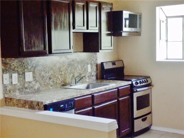 a kitchen with stainless steel appliances granite countertop a stove a sink and a microwave