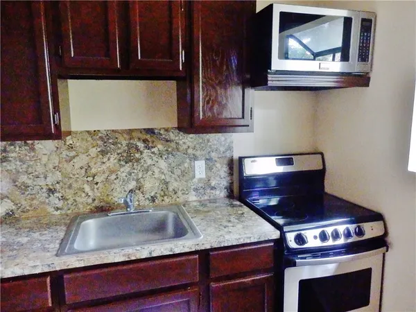 a kitchen with granite countertop a stove sink and cabinets