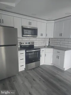 a kitchen with cabinets stainless steel appliances and wooden floor