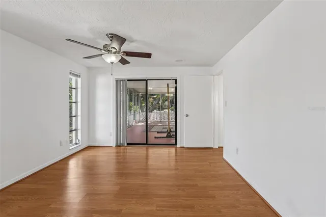 a view of an empty room with a window and wooden floor