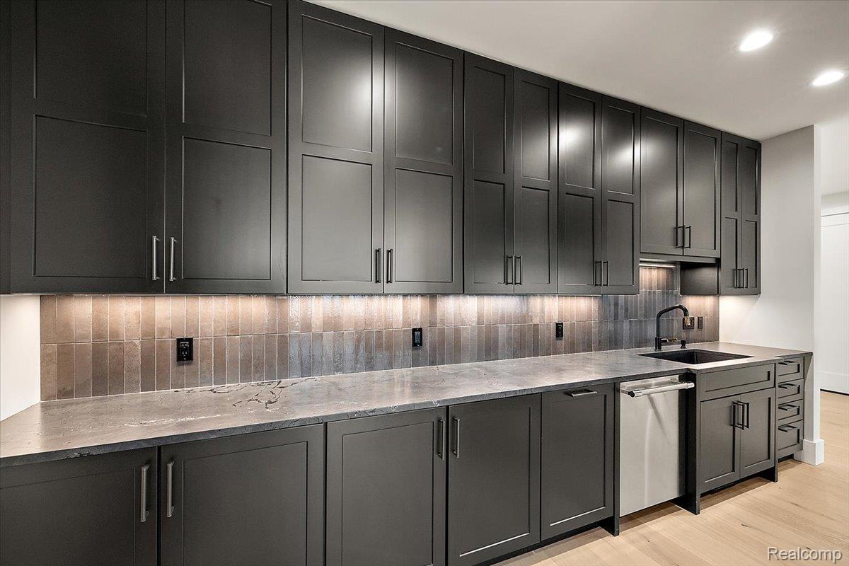 13459 Haddon Street Fenton, MI 48430 - Photo 6 of 84 Kitchen with dark cabinetry, backsplash, stainless steel dishwasher, recessed lighting, and light wood finished floors