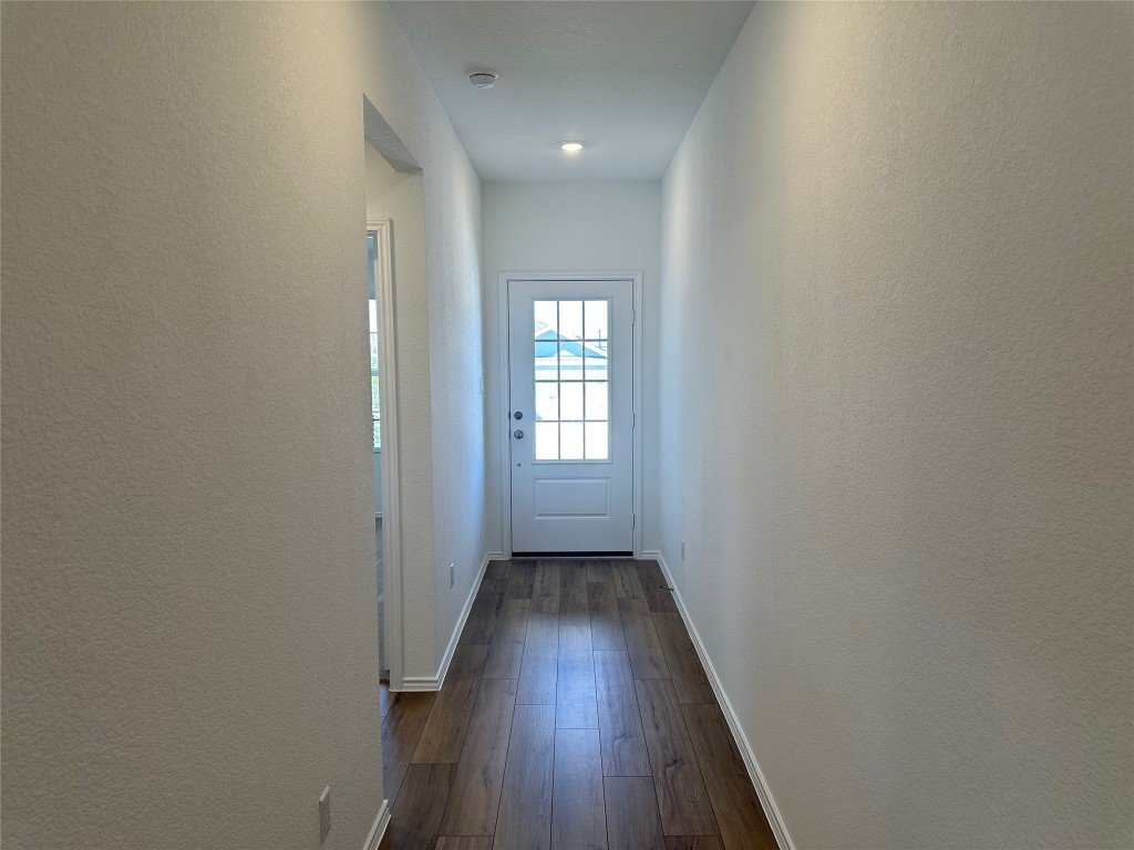 2513 Four Waters Loop Georgetown, TX 78628 - Photo 6 of 37 Doorway with a textured wall and hardwood / wood-style floors