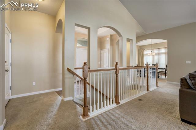 12442 Carmel Ridge Road Colorado Springs, CO 80921 - Photo 30 of 50 Hall featuring high vaulted ceiling, a notable chandelier, and light colored carpet