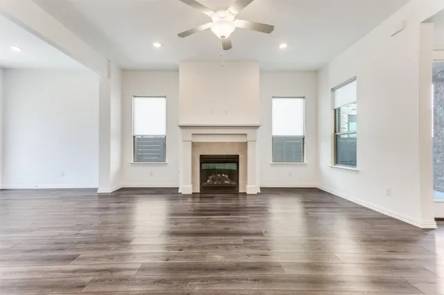 a view of an empty room with wooden floor fireplace and a window
