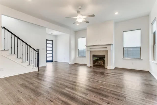 a view of an empty room with wooden floor fireplace and a window