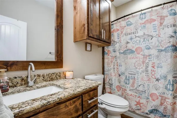a bathroom with a granite countertop sink a toilet and a mirror