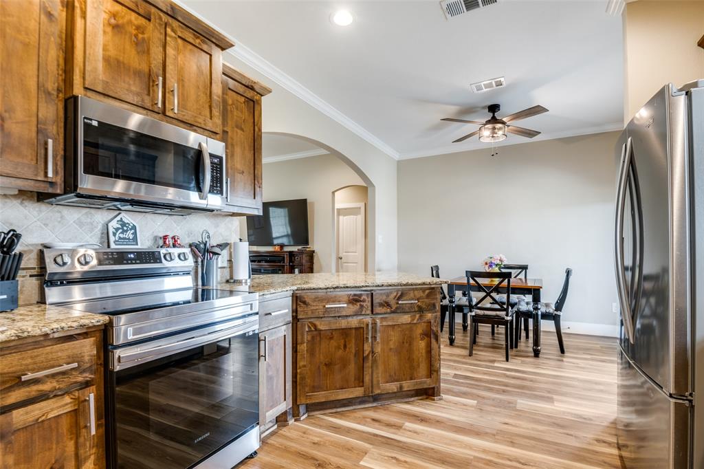2234 Westpoint Circle Terrell, TX 75161 - Photo 6 of 25 Kitchen with stainless electric range and microwave, alder wood cabinetry, granite counters, and open flow to the dining area and living space.