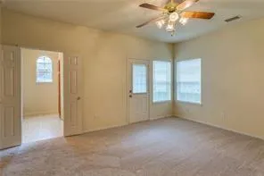 an empty room with windows and chandelier fan