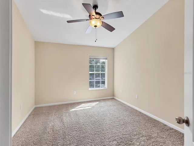 an empty room with a window and a ceiling fan