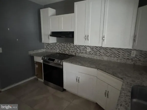 a kitchen with granite countertop white cabinets and stainless steel appliances